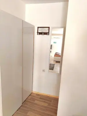 a room with a mirror and a white wall at City Center Sweet Apartment in Niš