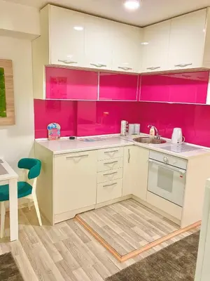 a kitchen with pink cabinets and a sink and a table at City Center Sweet Apartment in Niš
