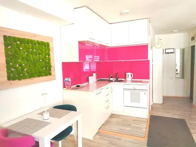 a kitchen with pink walls and a table and chairs at City Center Sweet Apartment in Niš