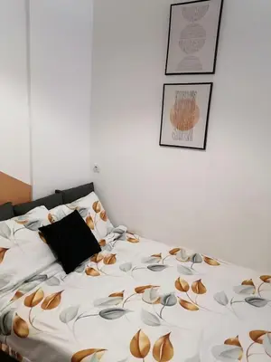 a bed with a white blanket with brown flowers on it at Studio Ukras in Vrnjačka Banja