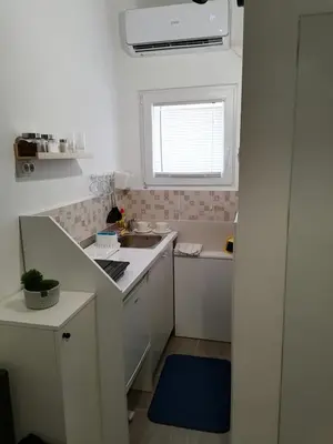 a small white kitchen with a sink and a window at Studio Ukras in Vrnjačka Banja