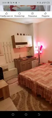 a bedroom with a bed and a kitchen with pink lights at Apartman Djordjevic in Vranje