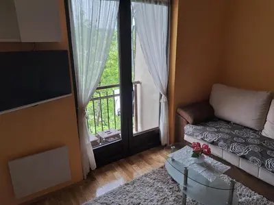a living room with a couch and a large window at Soko Banjica in Soko Banja