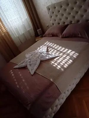 a bed with a blanket and a robe on it at Apartment Aleksandrija in Niš