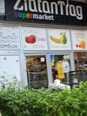 a store front of a supermarket with signs on the windows at Apartment Aleksandrija in Niš