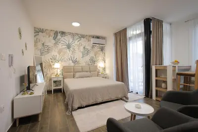 a bedroom with a bed and a living room at Adagio Apartmani in Vrnjačka Banja