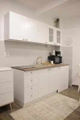 a kitchen with white cabinets and a sink at Adagio Apartmani in Vrnjačka Banja