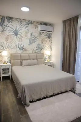 a bedroom with a large bed with blue and white wallpaper at Adagio Apartmani in Vrnjačka Banja