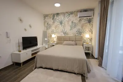 a bedroom with a bed and a flat screen tv at Adagio Apartmani in Vrnjačka Banja