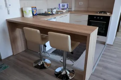 a kitchen with a wooden counter and two bar stools at Vamos a la playa in Jagodina