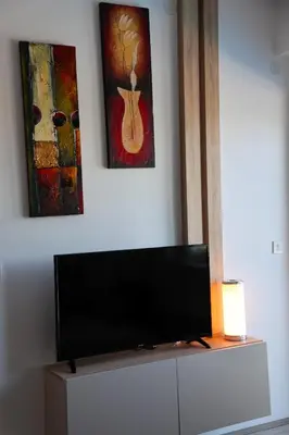 a flat screen tv on top of a dresser with paintings at Vamos a la playa in Jagodina