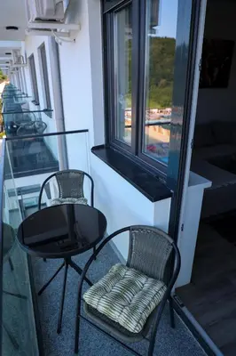 two chairs and a black table and chair on a balcony at Vamos a la playa in Jagodina