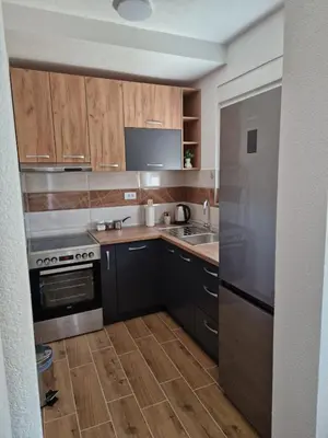 a kitchen with wooden cabinets and a stainless steel refrigerator at Apartman Nisić in Soko Banja