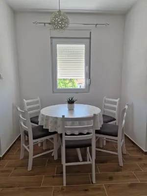 a white dining room table with chairs and a window at Apartman Nisić in Soko Banja