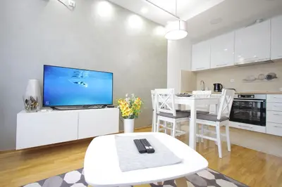 a white living room with a tv and a table at Vrnjačka oaza in Vrnjačka Banja