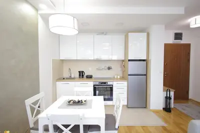 a kitchen with a white table and a white refrigerator at Vrnjačka oaza in Vrnjačka Banja