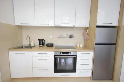 a kitchen with white cabinets and a stainless steel refrigerator at Vrnjačka oaza in Vrnjačka Banja