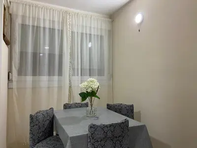 a table with chairs and a vase of flowers on it at Apartman Lea in Paraćin