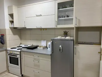a kitchen with white cabinets and a stainless steel refrigerator at Apartman Lea in Paraćin