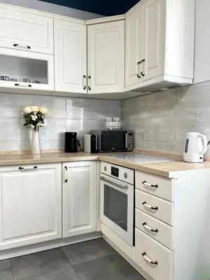 a white kitchen with white cabinets and a microwave at Lumo in Niš