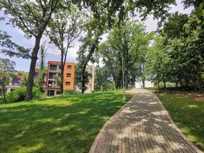 a brick path in a park with trees and a building at Centar Park Lux in Vrnjačka Banja
