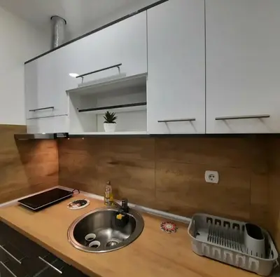 a kitchen counter with a sink and white cabinets at Studio Djukić Sokobanja in Soko Banja