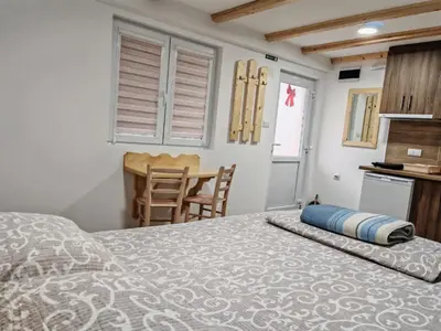 a bedroom with a bed and a kitchen and a table at Porta Simića in Ribarska Banja