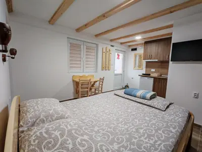 a bedroom with a large bed and a kitchen at Porta Simića in Ribarska Banja