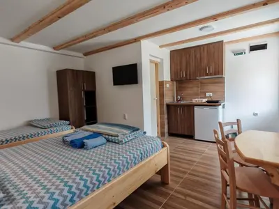 two beds in a room with a table and a kitchen at Porta Simića in Ribarska Banja
