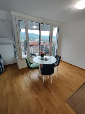 a room with a table and chairs and a large window at Apartman Popovic in Soko Banja