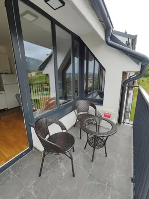 two chairs and a table on a balcony with windows at Apartman Popovic in Soko Banja