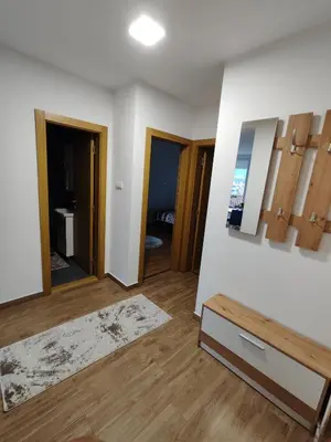 a room with white walls and wooden floors and a mirror at Apartman Popovic in Soko Banja