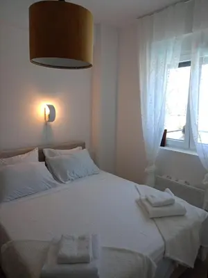 a bedroom with a white bed with a window at Jagodina Apartman Nastasija- gleda na Aqva park in Jagodina