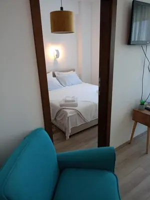 a mirror reflecting a bedroom with a bed and a blue chair at Jagodina Apartman Nastasija- gleda na Aqva park in Jagodina
