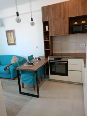 a kitchen with a table and a blue couch at Jagodina Apartman Nastasija- gleda na Aqva park in Jagodina