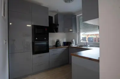 a kitchen with white cabinets and black appliances at Raj Petrović in Kovanluk