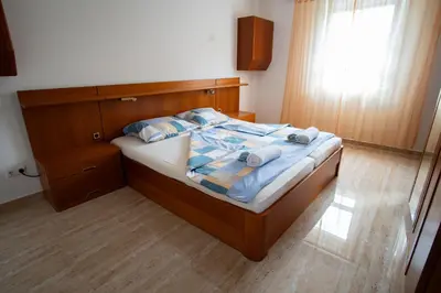 a bedroom with a bed with a wooden headboard and a window at Raj Petrović in Kovanluk