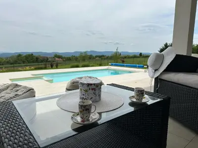 a table with two cups of tea on it next to a pool at Hacienda R - kuca sa bazenom in Siokovac