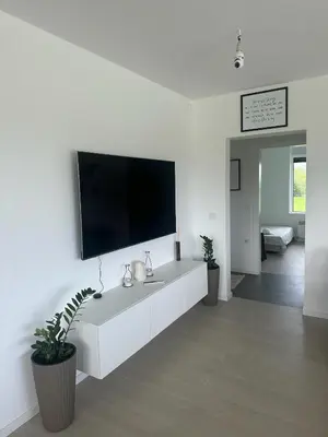 a white living room with a flat screen tv on a wall at Hacienda R - kuca sa bazenom in Siokovac