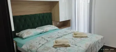 a bed with a green headboard and two towels on it at CENTAR CEPERKOVIC in Vrnjačka Banja
