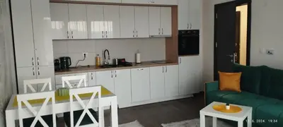 a kitchen with white cabinets and a green couch at CENTAR CEPERKOVIC in Vrnjačka Banja