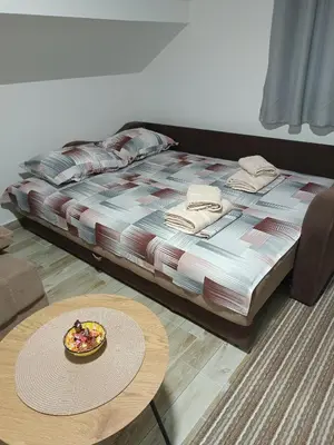 a bed with a table and a bowl of food on it at Apartman SJAJ in Soko Banja