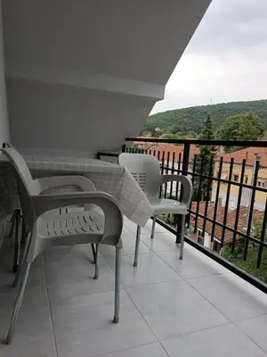 a balcony with two white chairs and a view of a hill at Apartman SJAJ in Soko Banja