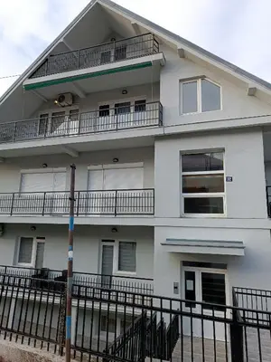 a white building with balconies and a fence at Apartman SJAJ in Soko Banja