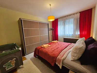 a bedroom with a bed and a window with red curtains at Apartman Purić in Pirot