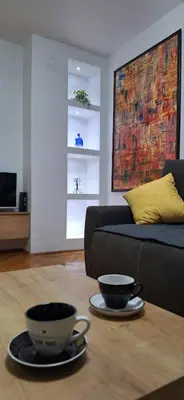 a living room with a couch and two cups on a table at Symphony in Pirot