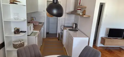 a small kitchen with white cabinets and a sink at Symphony in Pirot