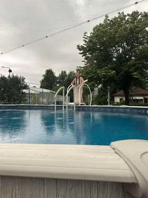 a man is standing next to a swimming pool at Vila Alex in Vrnjačka Banja