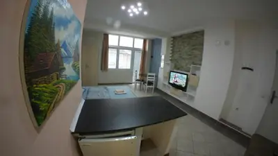 a kitchen with a counter and a tv in a room at Cozy Quiet Apartment Nis in Niš