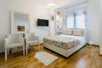 a bedroom with a bed and a chair and a mirror at Gracija in Jagodina